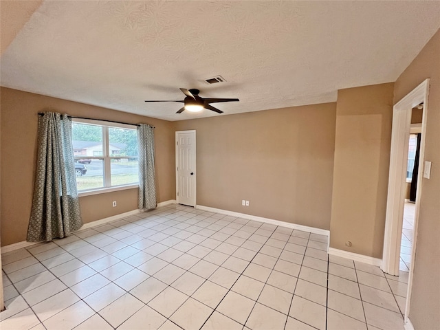 empty room with a textured ceiling, light tile patterned floors, and ceiling fan