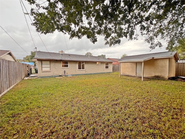 rear view of property featuring a storage shed and a lawn