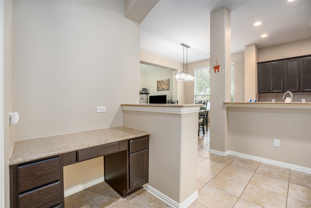 kitchen with sink, light tile patterned flooring, dark brown cabinetry, and decorative light fixtures