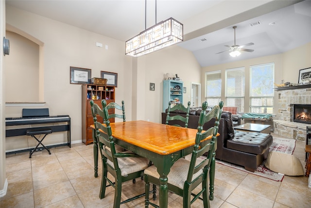 dining space with lofted ceiling, light tile patterned floors, a fireplace, and ceiling fan