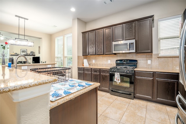 kitchen with gas stove, decorative backsplash, hanging light fixtures, dark brown cabinets, and ceiling fan