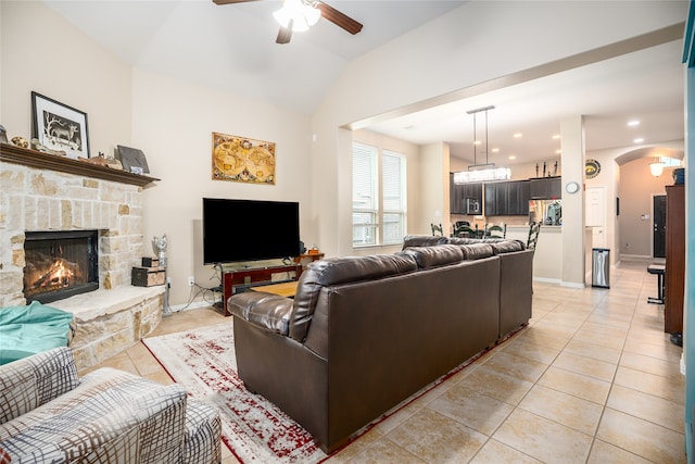 living room featuring ceiling fan, a stone fireplace, lofted ceiling, and light tile patterned floors