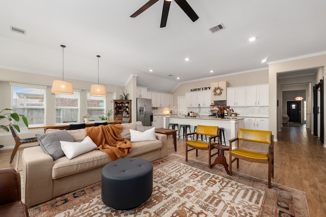 living room featuring ceiling fan, light wood-type flooring, and ornamental molding