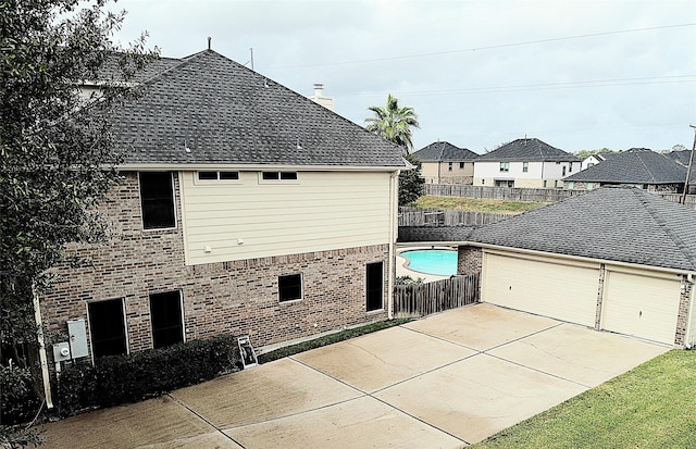 view of property exterior with a patio, a fenced backyard, a chimney, brick siding, and driveway