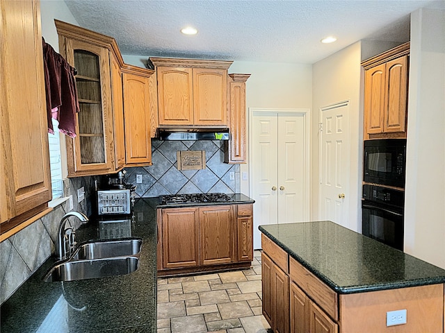 kitchen with a textured ceiling, sink, black appliances, and decorative backsplash