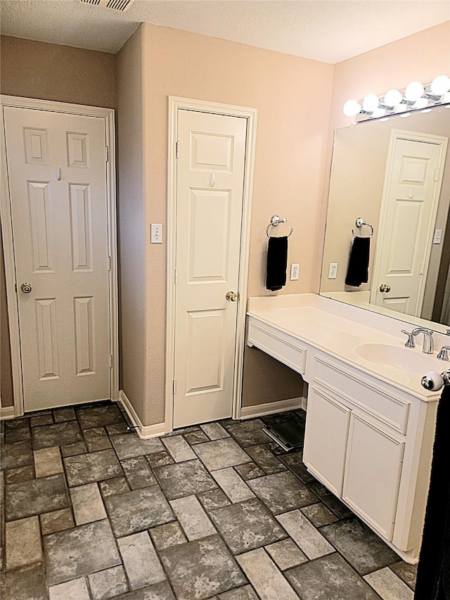 bathroom featuring baseboards, visible vents, brick floor, and vanity