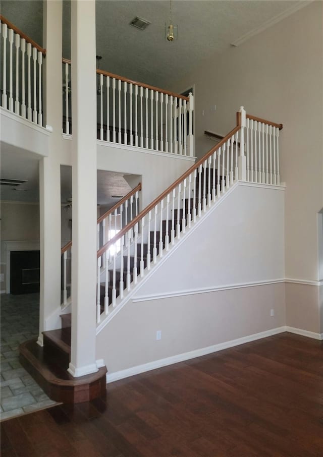 stairs with baseboards, a towering ceiling, wood finished floors, and visible vents