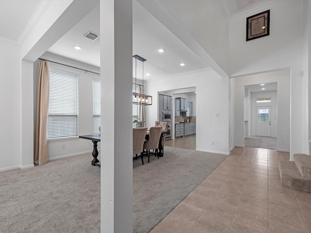 entrance foyer with light carpet, crown molding, and an inviting chandelier