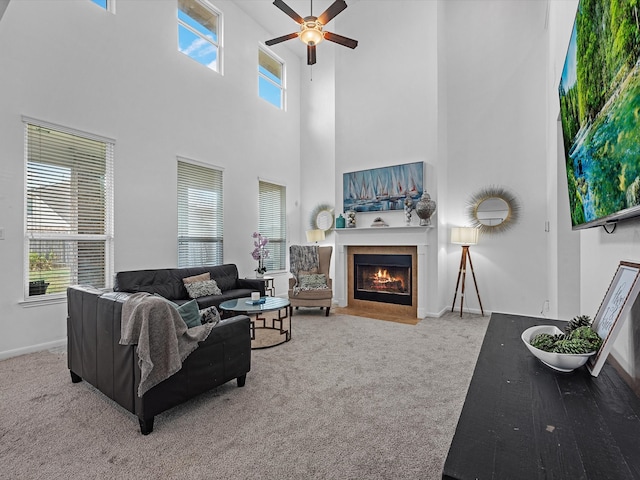 living room featuring a towering ceiling, carpet floors, and ceiling fan