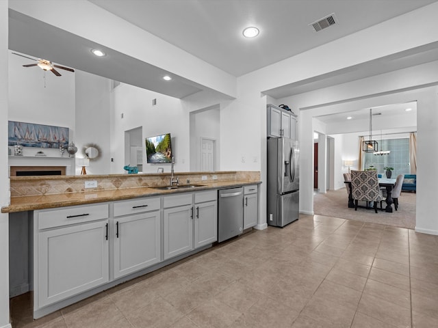 kitchen featuring hanging light fixtures, sink, light colored carpet, appliances with stainless steel finishes, and ceiling fan