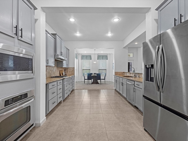 kitchen with sink, light tile patterned flooring, stainless steel appliances, gray cabinets, and light stone counters