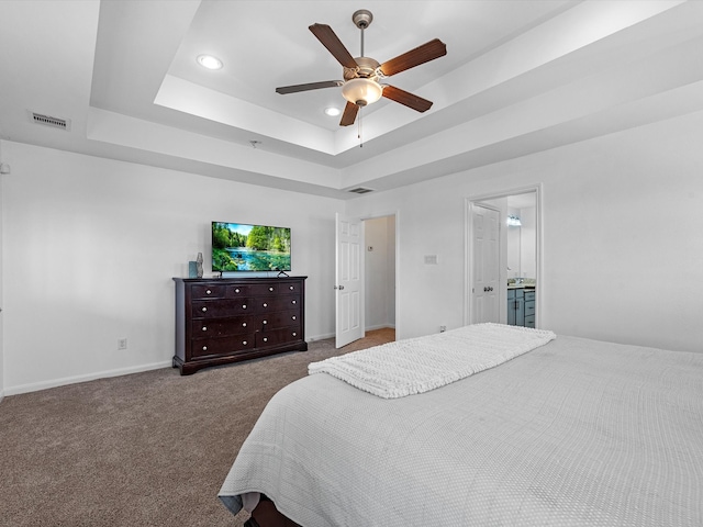 carpeted bedroom featuring connected bathroom, ceiling fan, and a raised ceiling