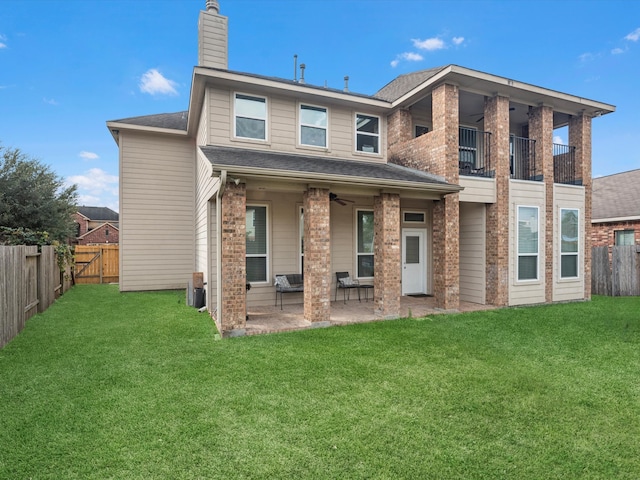 rear view of house with a patio, ceiling fan, a lawn, and a balcony