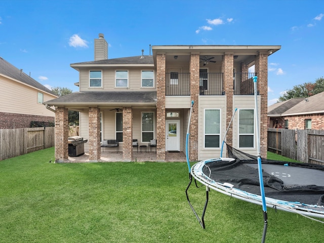 rear view of property featuring a patio area, a lawn, and a trampoline