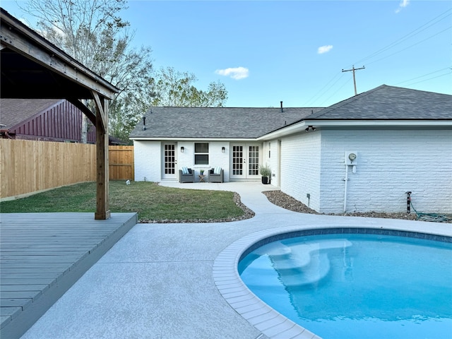 view of swimming pool with a wooden deck, a yard, and french doors