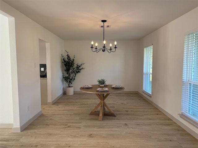 dining room with light wood-type flooring and an inviting chandelier