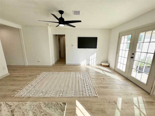 empty room with ceiling fan, french doors, and light hardwood / wood-style floors