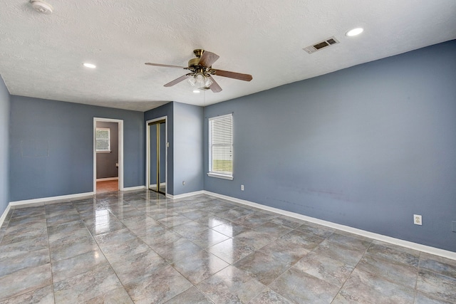 empty room with a textured ceiling and ceiling fan