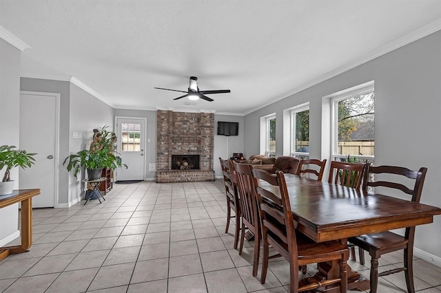 tiled dining area with a brick fireplace, ceiling fan, and crown molding