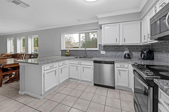 kitchen with stainless steel appliances, kitchen peninsula, decorative backsplash, white cabinets, and sink