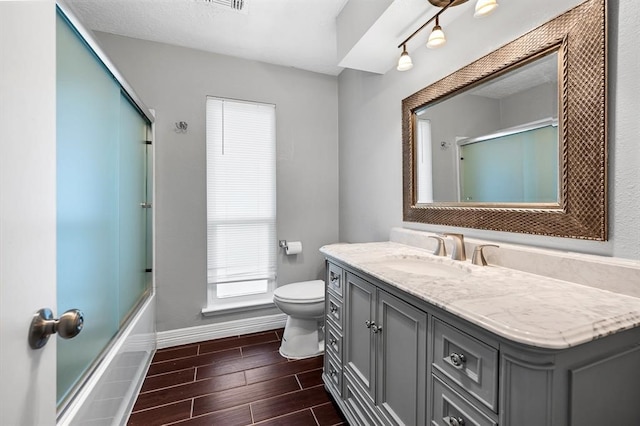 full bathroom featuring toilet, combined bath / shower with glass door, and vanity