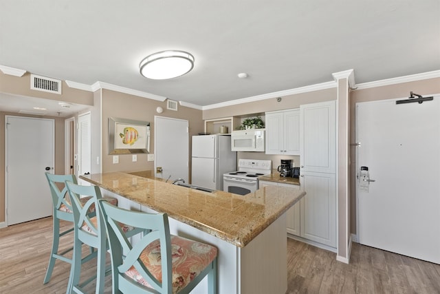 kitchen featuring white appliances, light hardwood / wood-style flooring, kitchen peninsula, and a kitchen breakfast bar