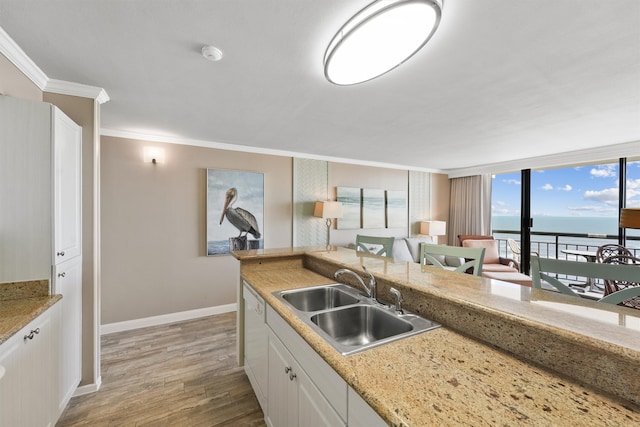 kitchen featuring ornamental molding, sink, white cabinets, a water view, and light hardwood / wood-style floors