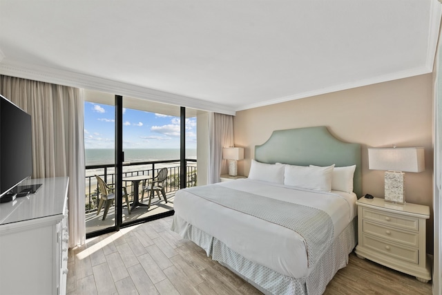 bedroom with access to exterior, light hardwood / wood-style floors, expansive windows, a water view, and ornamental molding