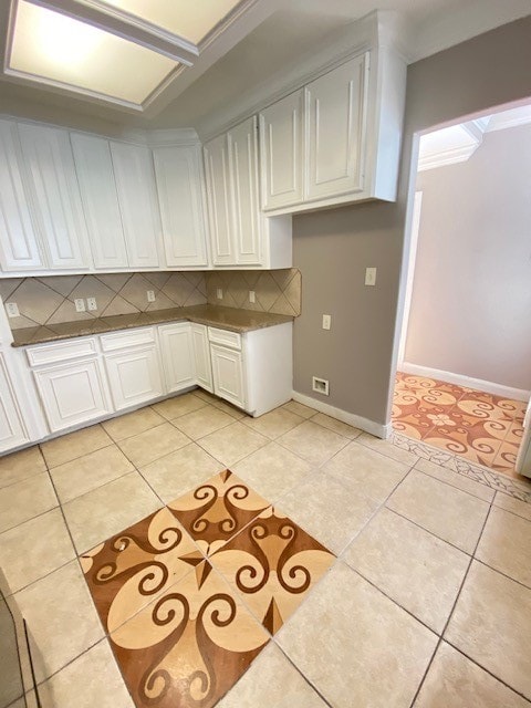 kitchen featuring tasteful backsplash, light tile patterned flooring, and white cabinets