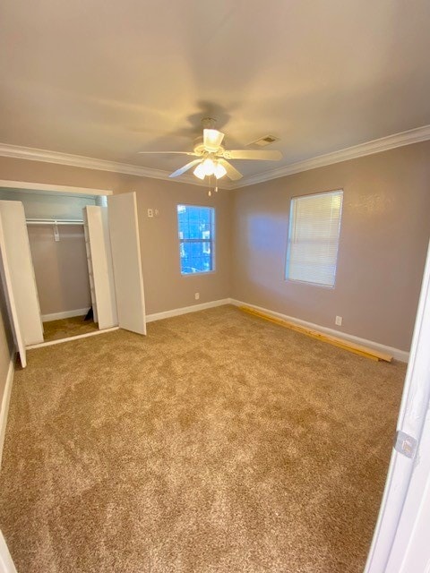 unfurnished bedroom with a closet, ceiling fan, crown molding, and carpet