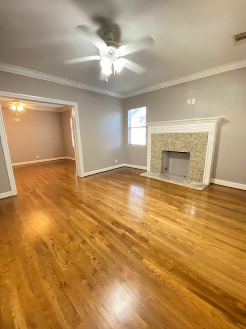 unfurnished living room with crown molding, hardwood / wood-style flooring, a fireplace, and ceiling fan