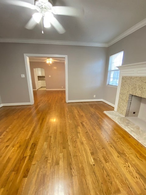 unfurnished living room with ornamental molding, a high end fireplace, hardwood / wood-style flooring, and ceiling fan