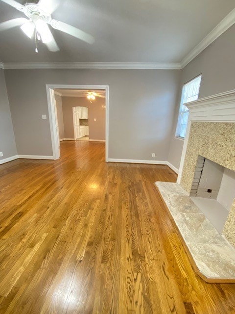 unfurnished living room with ceiling fan, crown molding, a high end fireplace, and hardwood / wood-style floors