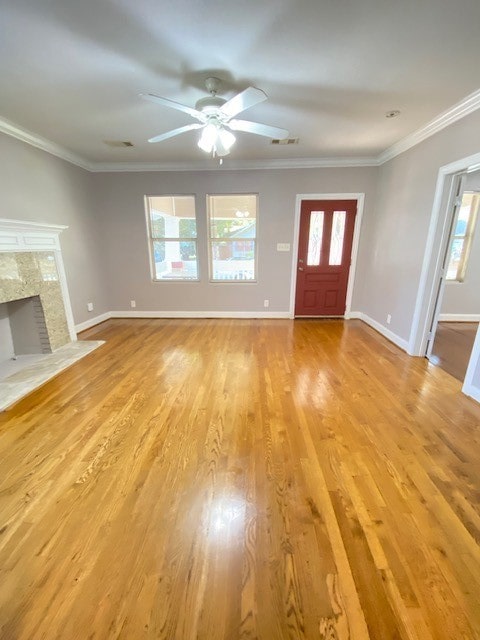 unfurnished living room featuring light hardwood / wood-style floors, ornamental molding, plenty of natural light, and a high end fireplace