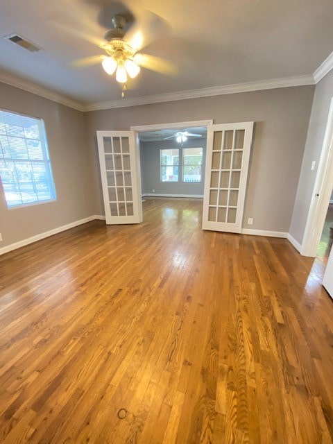 unfurnished room with french doors, crown molding, wood-type flooring, and ceiling fan