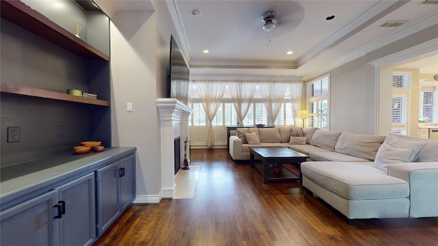 living room featuring ornamental molding, dark hardwood / wood-style floors, a tray ceiling, and ceiling fan