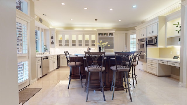 kitchen featuring a kitchen island, built in appliances, crown molding, a kitchen bar, and white cabinetry