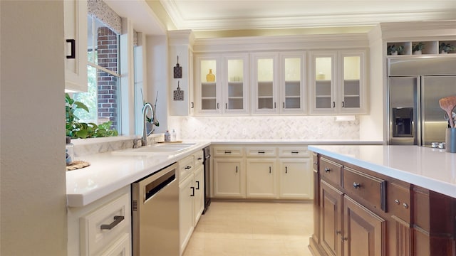 kitchen featuring appliances with stainless steel finishes, sink, backsplash, white cabinets, and ornamental molding