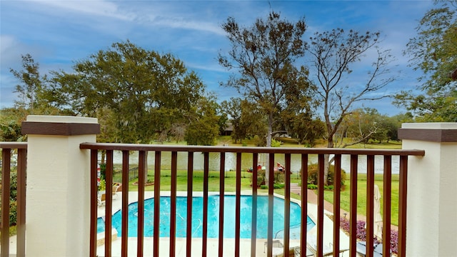 view of swimming pool featuring a water view and a lawn