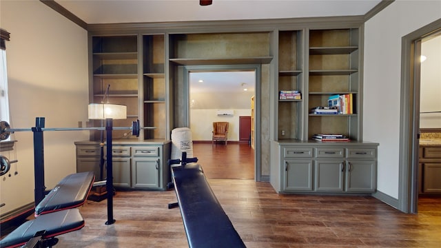 exercise area with dark wood-type flooring and ornamental molding