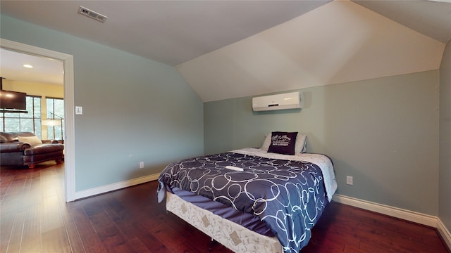 bedroom featuring vaulted ceiling, a wall unit AC, and hardwood / wood-style flooring