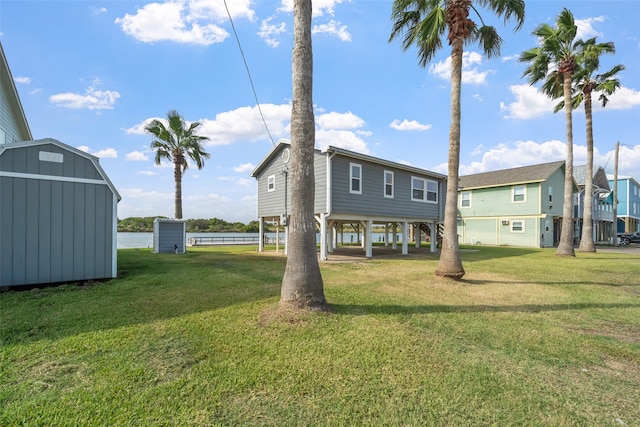 rear view of property with a storage unit and a lawn