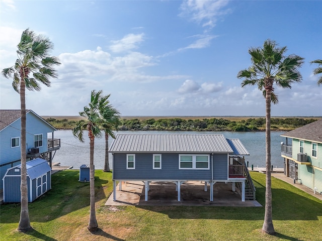 rear view of house with a patio area, a yard, and a water view