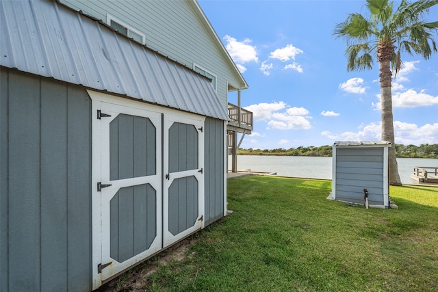 view of outdoor structure featuring a water view and a lawn