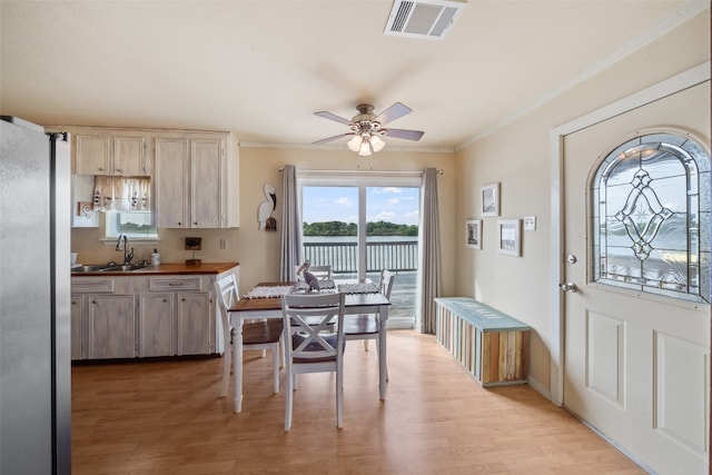 interior space featuring stainless steel fridge, ceiling fan, light hardwood / wood-style floors, crown molding, and sink