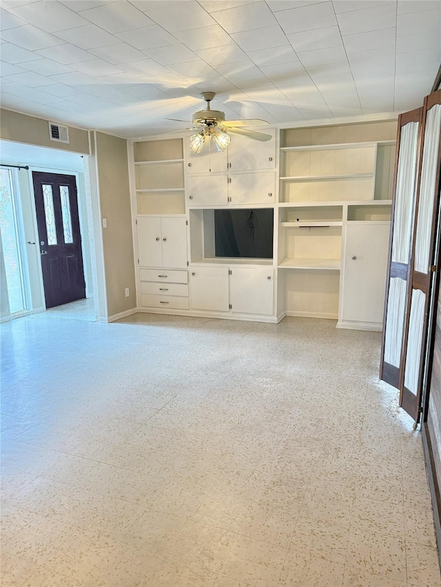 unfurnished living room with visible vents, built in shelves, a ceiling fan, and light floors
