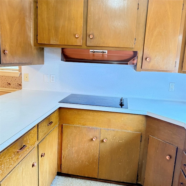 kitchen with under cabinet range hood, light countertops, and black electric stovetop