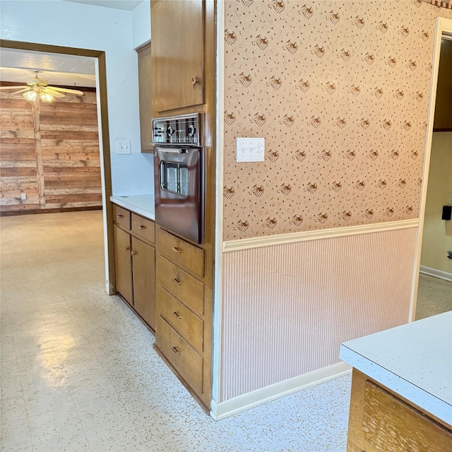 kitchen with oven, wainscoting, light floors, and a ceiling fan