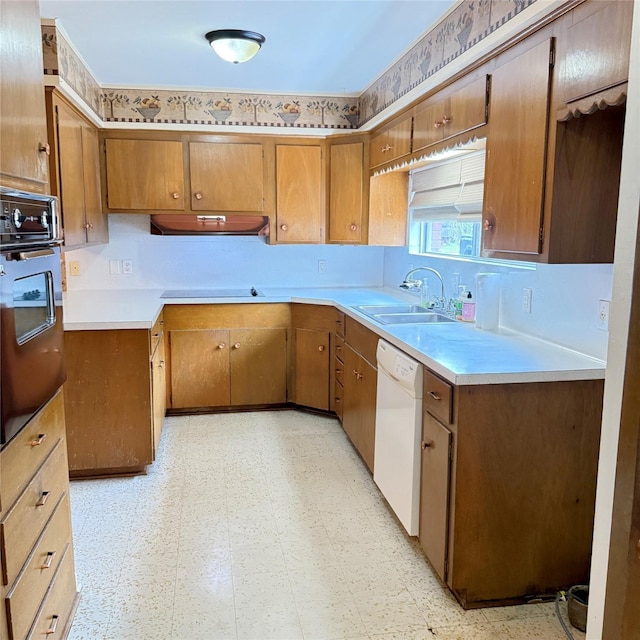 kitchen featuring black oven, exhaust hood, light floors, dishwasher, and a sink