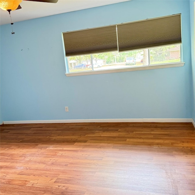 empty room with baseboards, a ceiling fan, and wood finished floors